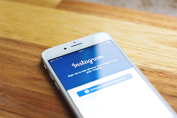 weißes iPhone auf einem Holztisch mit dem Anmeldebildschirm für Instagram